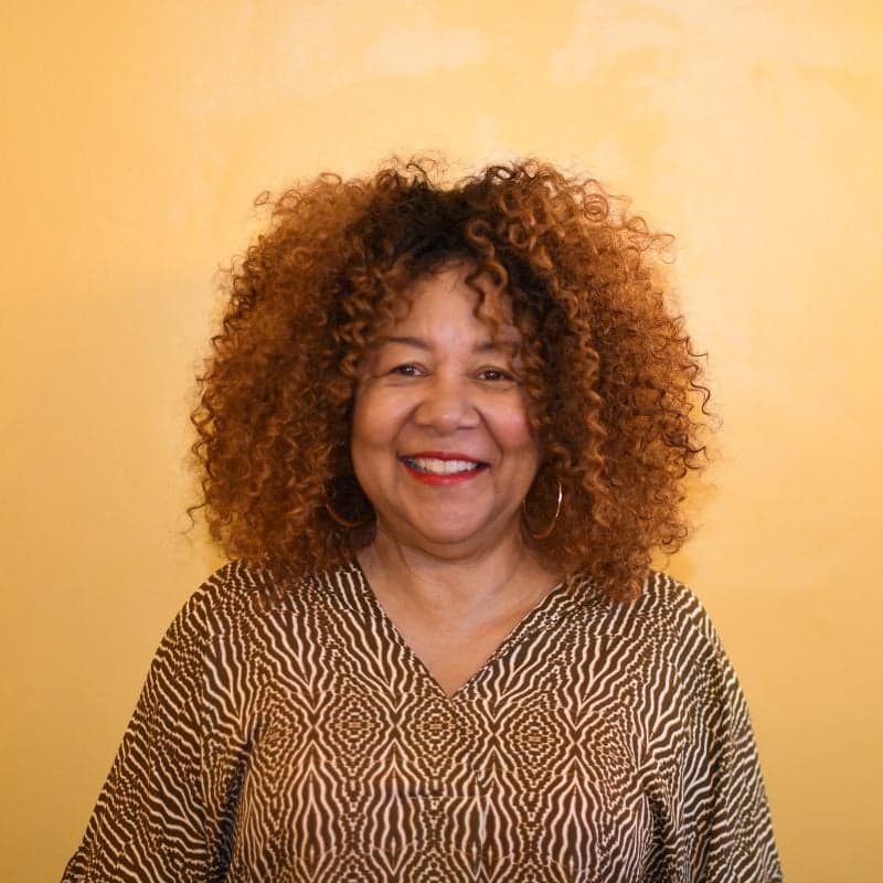 Smiling woman giving a piggyback ride to a laughing young girl.